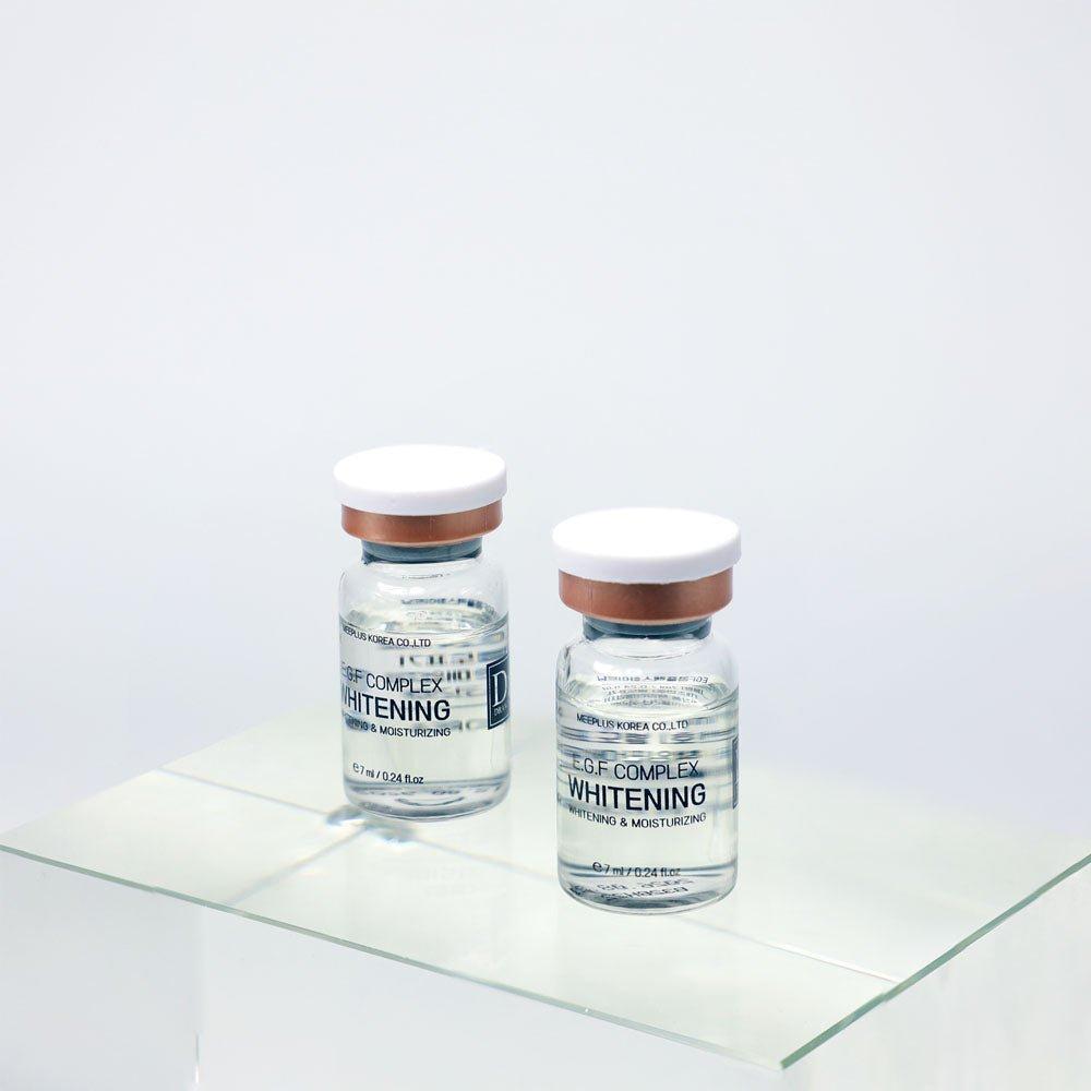 
                  
                    Two skincare vials labeled 'EGF Complex Whitening' on a reflective surface with a light grey background.
                  
                